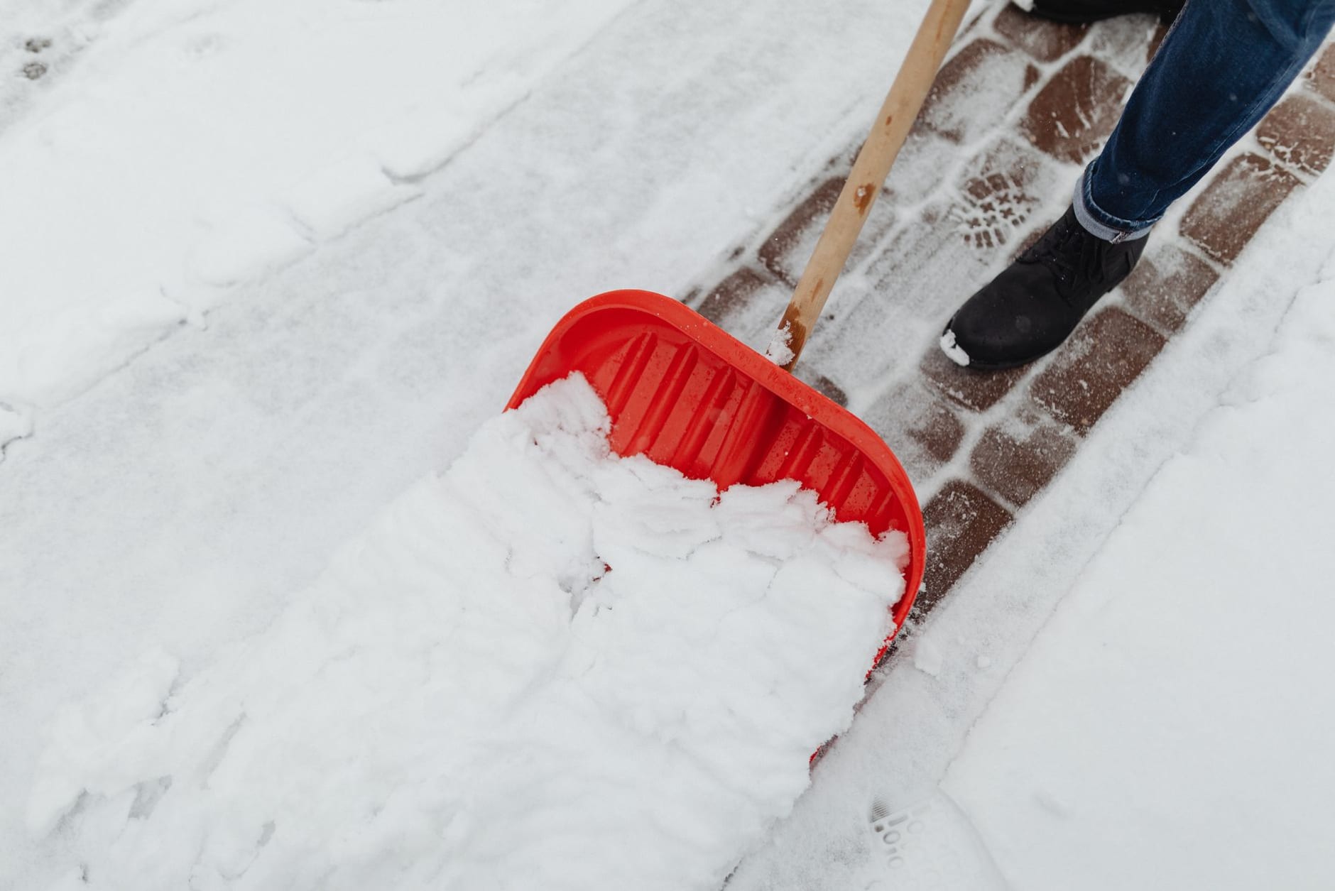 Schneeschieber räumt einen gepflasterten Gehweg frei – Winterdienst am Bayerischen Untermain